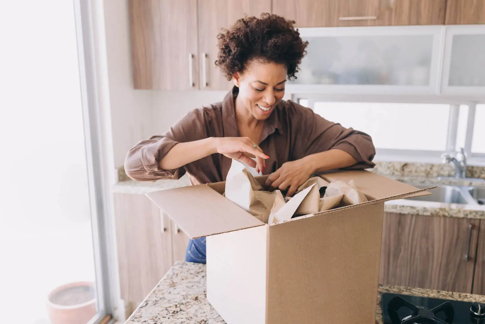 A woman unpacking boxes in a new, empty kitchen